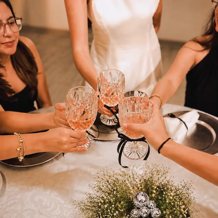 Cuatro invitadas brindan con copas de cristal alrededor de una mesa en Merak Eventos